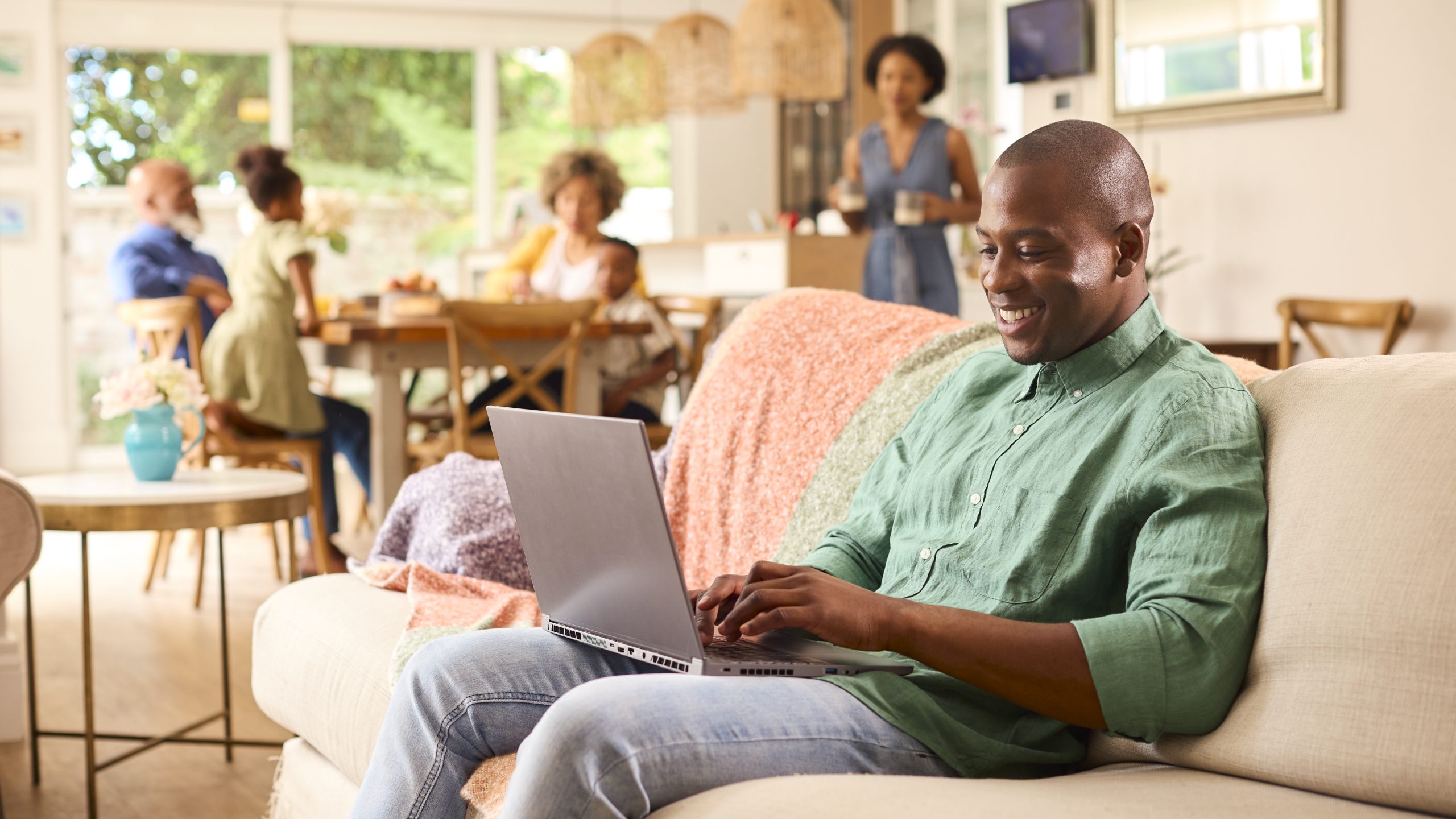Looking At Laptop With Grandparents And Children In Background