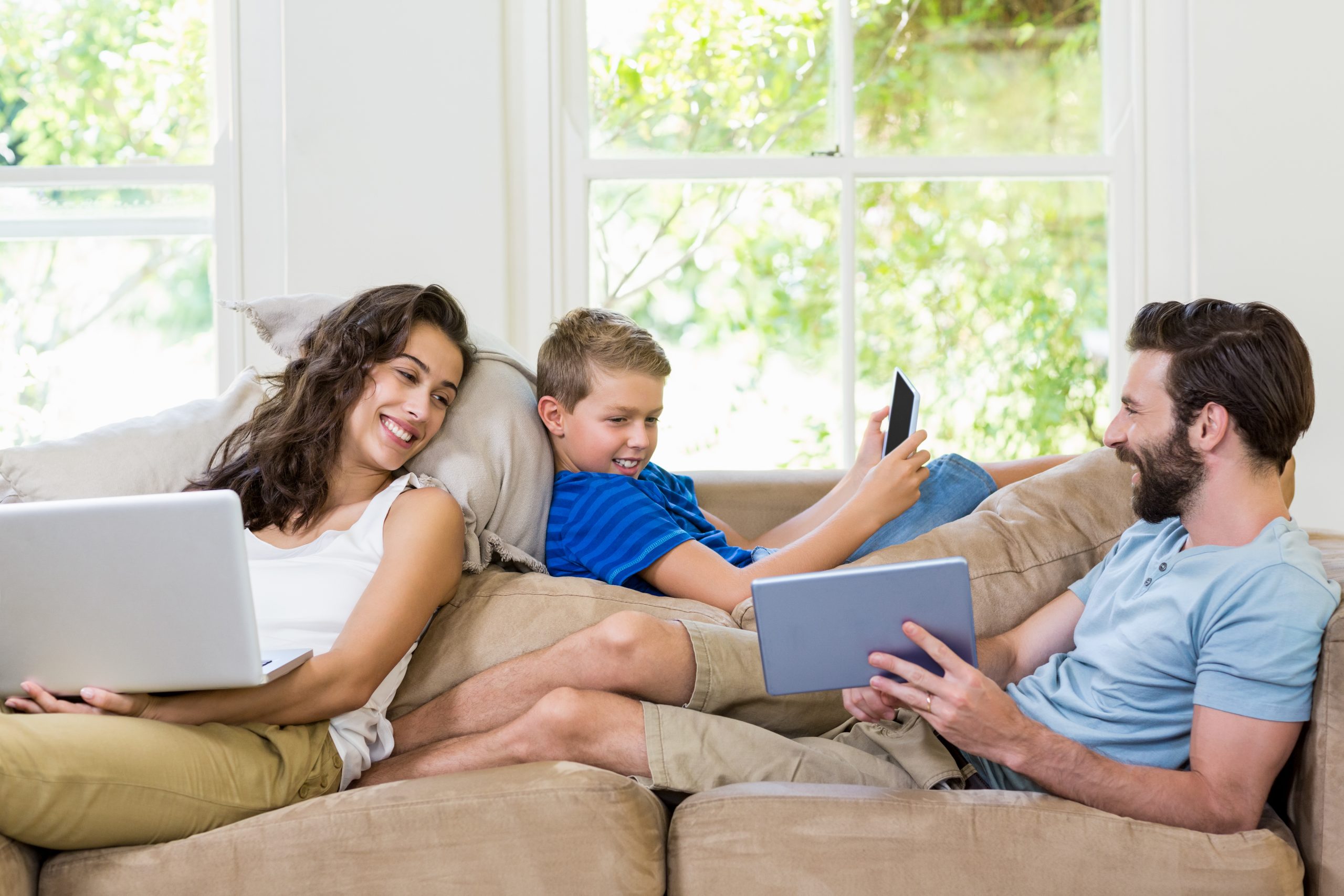 Parents and son using a laptop, tablet and phone