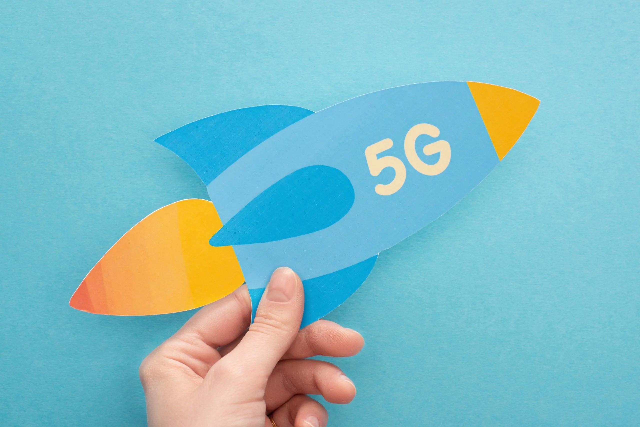 woman holding paper rocket with 5g lettering on blue background